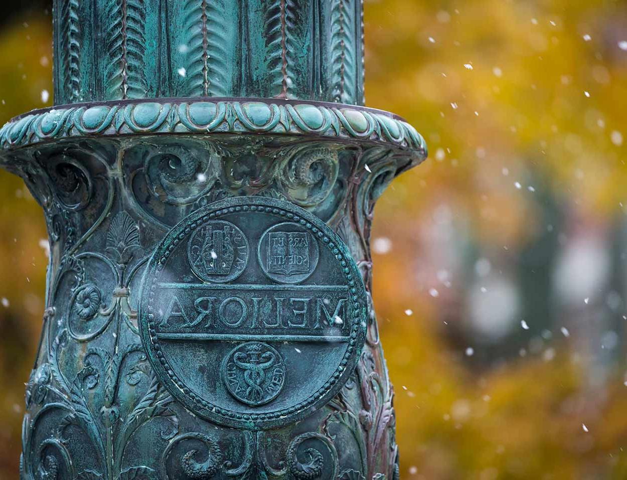 Meliora seal on flagpole in snow at University of Rochester